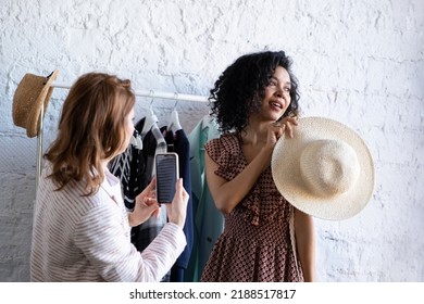 Happy Women Try On Things At Fashion Shop And Taking Photo On Phone. Choose Casual Clothes, Shoes, Hats, Bags, Jewellery. Idea Of Exchange Old Wardrobe. Zero Waste Shopping, Reduce And Reuse