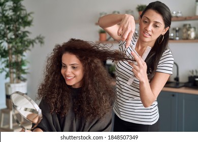 Happy women while trimming their hair at home                                 - Powered by Shutterstock