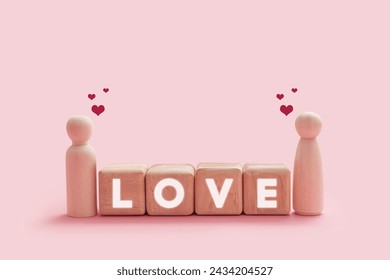 Happy wooden couple figures isolated on a pink background. The couple smiling with hearts shape on their head and word Love on wooden cube