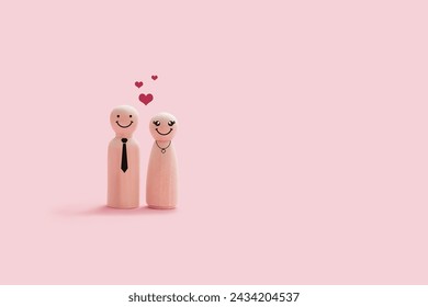 Happy wooden couple figures isolated on a pink background. The couple smiling and stand close together with hearts shape on their head