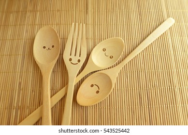 Happy wooden forks and spoons on wood texture of dining table. Concept about happiness and friendship.