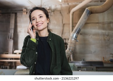 Happy Woodworker Talking On Mobile Phone In Workshop