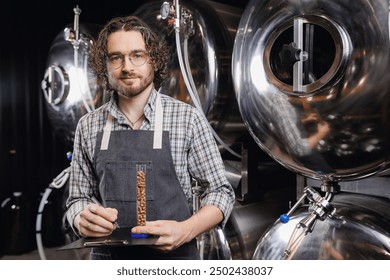 Happy worker man with clipboard control brewery process. Portrait owner of craft beer factory background tank equipment. - Powered by Shutterstock