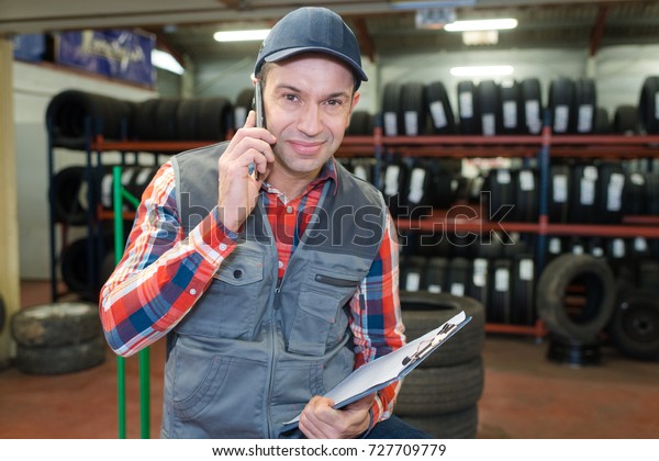 happy worker\
on the phone in a tire repair\
service