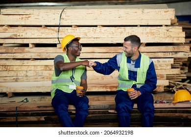 Happy workers having fun and fist bumping during their coffee break at lumber warehouse.  - Powered by Shutterstock