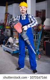 happy  working man practicing his skills with pneumatic drill at workshop