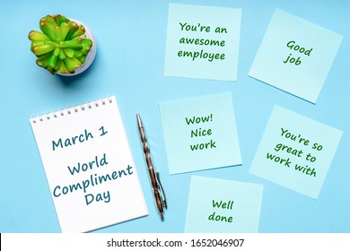 Happy World Compliment Day. Office desk with plant, notebook, pen and paper slips with compliments text for office worker such as GOOD JOB. Greeting card for world compliment day. Flat lay, top view