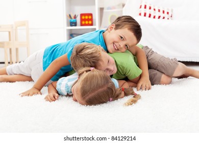 Happy Wrestling Kids Laying In A Pile Indoors - Focus On The Middle Child