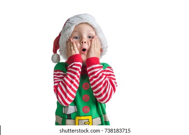 Happy Xmas And New Year Holiday! Shocked And Surprised Kid With Red Christmas Hat With Head In Hands. Cheerful Smiling Little Boy Opens His Mouth In Surprise.