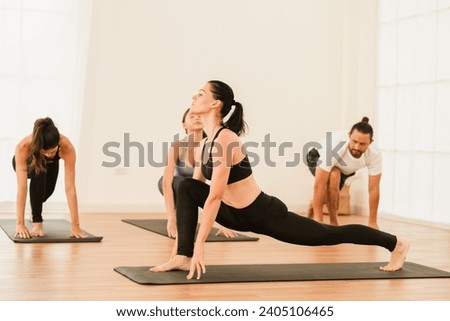 Happy yoga instructor enjoying teaching a group class to young people in the studio