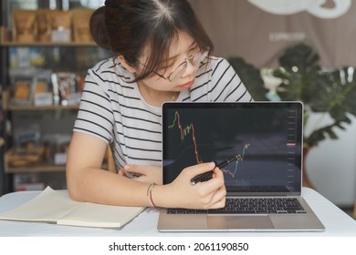 Happy Young Adult Asian Businesswoman, Female Trader, Investor Is Using Computer Laptop With Graph Chart For Teaching On Business Money Investment, Stock Market Or Cryptocurrency Trading As Bitcoin.