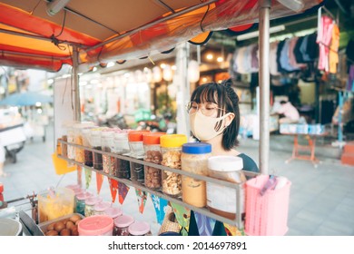 Happy young adult asian foodie woman order vendor asia dessert. Wear face mask for virus. People traveling with new normal lifestyle at outdoor street night food market.