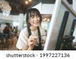 Happy young adult asian woman painting brush on canvas at workshop art lesson class. People leisure with creativity education lifestyle for mental health concept.