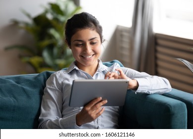Happy young adult indian woman hold digital pad tablet computer sit on sofa at home, smiling lady using app reading electronic book relax in living room enjoy browsing web on modern device technology - Shutterstock ID 1606121146