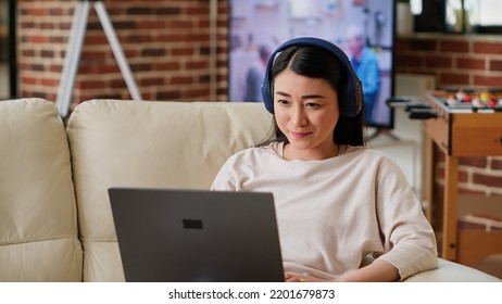 Happy Young Adult Person Watching Online Streaming Series Of Favourite Internet Show While Sitting On Sofa At Home. Asian Woman Enjoying Watching Entertaining Comedy Movies And Content On Laptop.