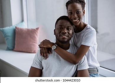 happy young african american couple in white t-shirts smiling at camera at home  - Shutterstock ID 1044423010