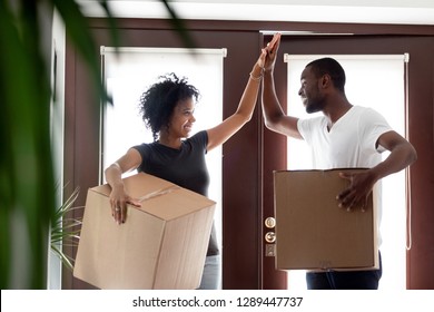 Happy young african american couple tenants give high five celebrate moving day in own house hold boxes, excited black family first time buyers owners in new home, mortgage goals, relocation concept