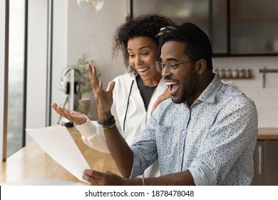 Happy young African American couple feel euphoric read good unbelievable news in paper letter correspondence. Overjoyed biracial man and woman triumph get pleasant message in paperwork.
