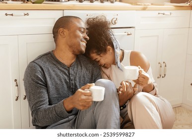 Happy young African American couple sitting in modern own kitchen at home drink coffee or tea enjoy sunny morning together. Smiling millennial man and woman celebrate relocation moving to new house. - Powered by Shutterstock