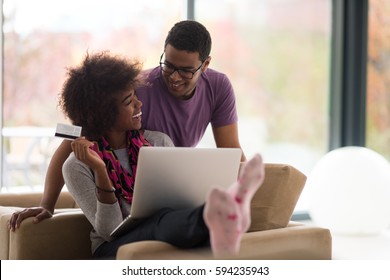 Happy Young African American Couple Shopping Online Through Laptop Using Credit Card At Home