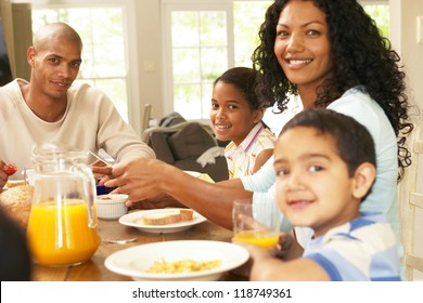 Happy Young African American Family Seated Around A Table Enjoying A Healthy Breakfast Together In A Relaxed Start To The Day