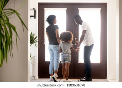 Happy Young African American Family Stand In Hallway Hold Hands Go Out For A Walk, Smiling Millennial Black Dad Open Doors, Taking Wife And Daughter Outside Have Fun. New Beginning Concept