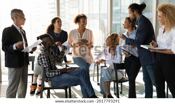 Happy young african american female leader\
holding negotiations meeting with friendly diverse colleagues\
gathered at table in modern office room, discussing project ideas\
or developing strategy.