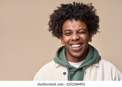 Happy young African American gen z guy winking isolated on beige background. Playful ethnic teen student, cool curly generation z teenager smiling with white perfect teeth, close up portrait. - Shutterstock ID 2252584901
