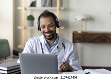 Happy Young African American GP Doctor In Headphones Holding Distant Web Camera Meeting, Giving Professional Consultation To Patient Using Computer Video Call App, Virtual Healthcare Event Concept.