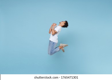 Happy young african american guy in casual white t-shirt posing isolated on pastel blue wall background studio portrait. People lifestyle concept. Mock up copy space. Jumping, doing winner gesture - Shutterstock ID 1765471301