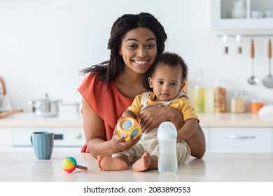 Happy Young African American Mother And Her Cute Toddler Baby Posing In Kitchen Interior, Portrait Of Beautiful Black Mom And Adorable Infant Child Looking And Smiling At Camera At Home, Copy Space