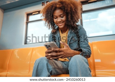 Happy young African American traveling woman passenger smile and using smart mobile phone in subway train station. Enjoying travel