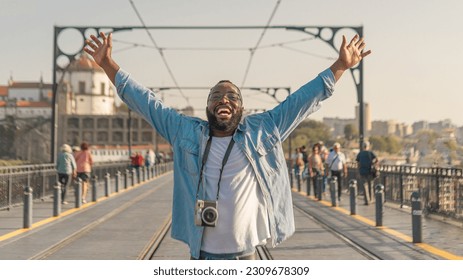 Happy Young african american traveller man with cmera on the Dom Luis Bridge, Porto. Travel in Portugal