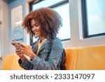 Happy young African American woman passenger smile and using smart mobile phone in subway train station.