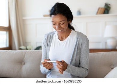 Happy Young African American Woman Hold Pregnancy Test Look At Positive Result. Smiling Millennial Healthy Biracial Female Check Being Pregnant On Medical Ovulation Stick Or Kit. Maternity Concept.