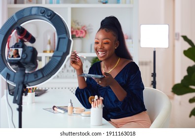 happy young african american woman streaming a beauty vlog from home, online content creator applying a makeup on - Shutterstock ID 1911163018