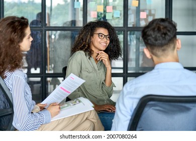 Happy young African American woman brainstorming marketing ideas about project strategy among diverse multiracial coworkers, business startup creative team or students group in office holding papers.