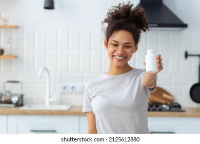 Happy Young African American Woman Holding Bottle Of Dietary Supplements Or Vitamins In Her Hands. Close Up. Healthy Lifestyle Concept