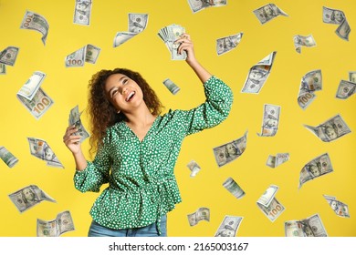 Happy Young African American Woman With Money And Falling American Dollars On Yellow Background