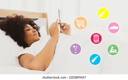 Happy Young African American Woman Relaxing At Home Wakes Up In The Morning Plays Her Favorite Smartphone Shopping Orders Online Shoe Delivery, Restaurant Reservations, Spa Salon, Musical Instruments.