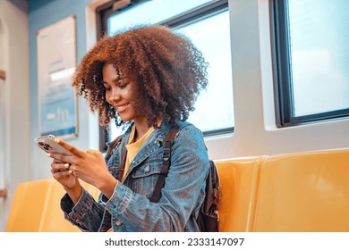 Happy young African American woman passenger smile and using smart mobile phone in subway train station.