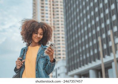 Happy young African American woman using social media on mobile phone on street in a urban city. copy space. - Powered by Shutterstock