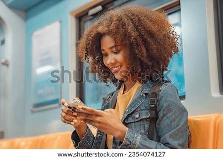 Happy young African American woman passenger smile and using smart mobile phone in subway train station.