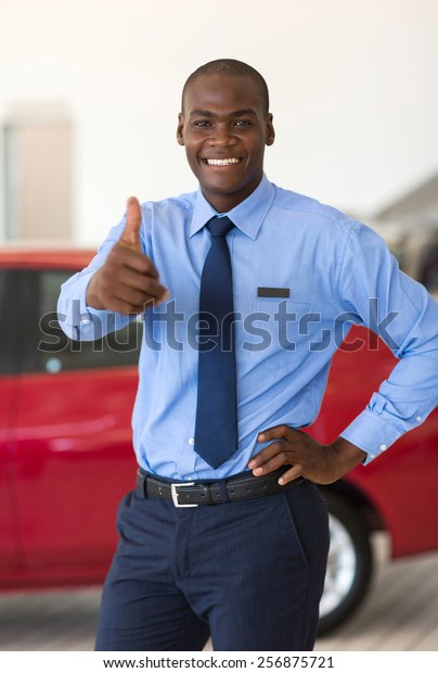 happy\
young african car salesman thumb up in\
showroom