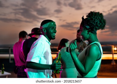 Happy young African couple dancing against their friends at rooftop party - Shutterstock ID 2018213657