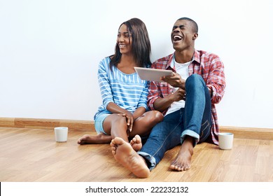 happy young african couple looking on tablet computer for new home furnishings for their apartment