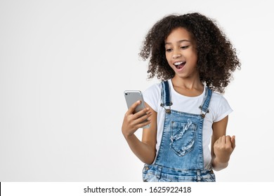 Happy Young African Girl Kid Using Mobile Phone Make Winner Gesture Posing Isolated Over White Background