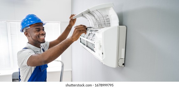 Happy Young African Male Technician Repairing Air Conditioner