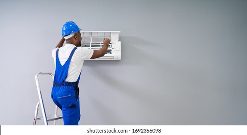 Happy Young African Male Technician Repairing Air Conditioner - Powered by Shutterstock