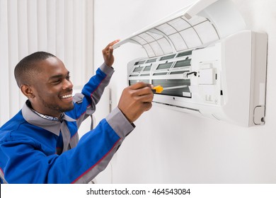 Happy Young African Male Technician Repairing Air Conditioner - Powered by Shutterstock